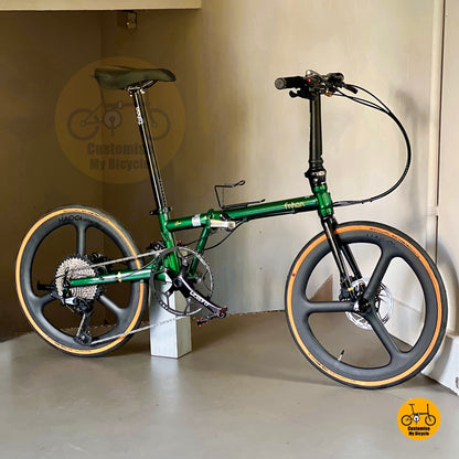 Green folding bicycle with black seat and tires on a white background
