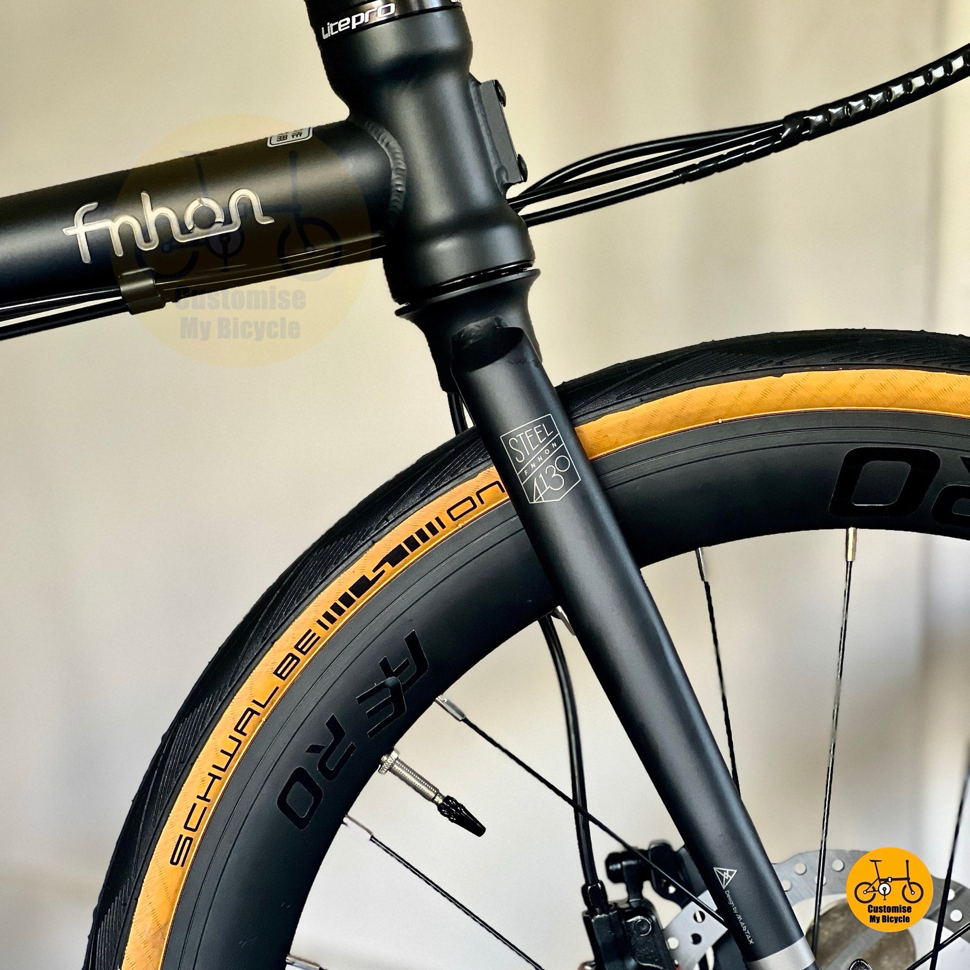 SCHWALBE tan wall tyres on matte black folding bicycle  
