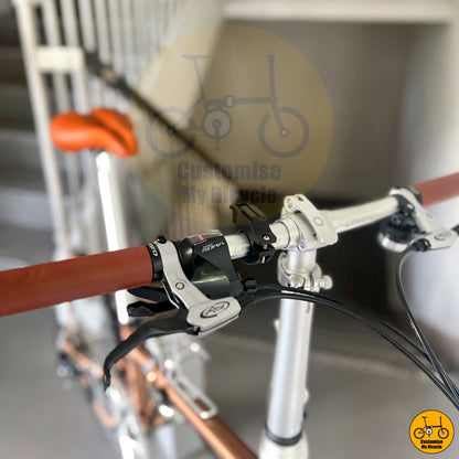 Sleek rose gold folding bicycle with a comfortable brown saddle
