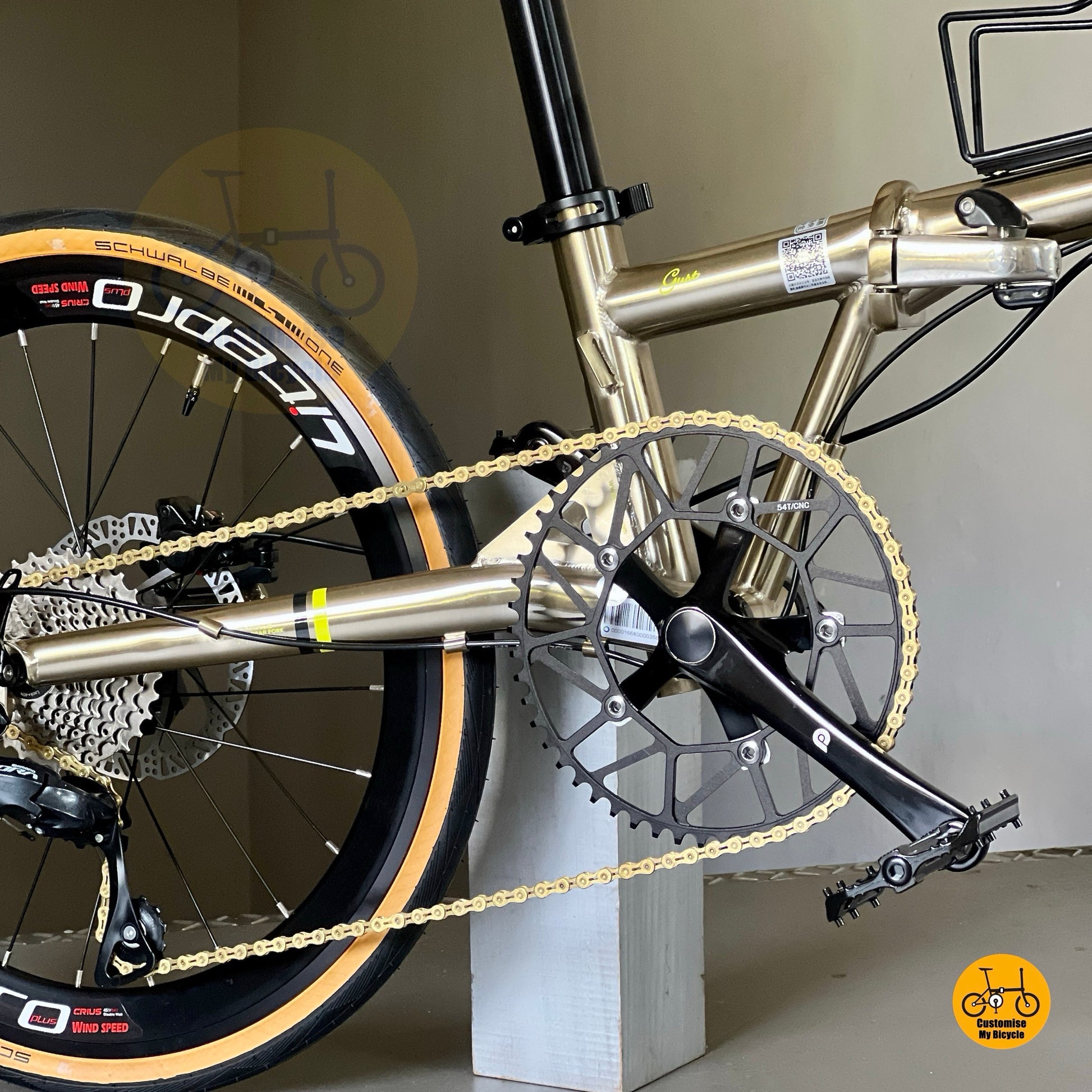 Angled view focusing on crankset and chainring of Fnhon Gust 22” titanium gold, showing polished metallic frame reflections.

