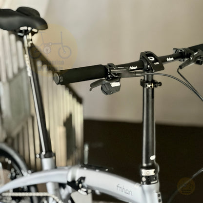 Close-up of a folding bicycle handlebar area with black grips, black handlebar clamp, and a light gray frame. The brand name 'fnhon' is visible on the frame and handlebar.