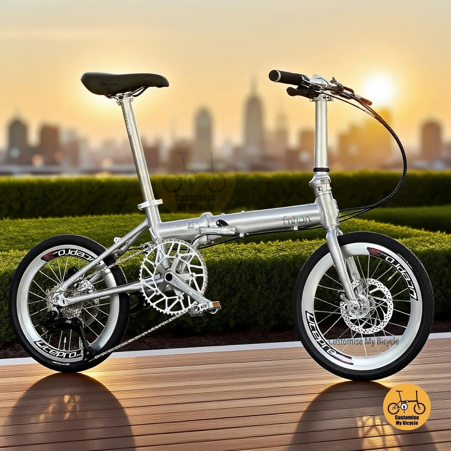 Full side view of Fnhon Zephyr 18-inch folding bike in polished silver, displayed on wooden deck with city skyline at sunset.
